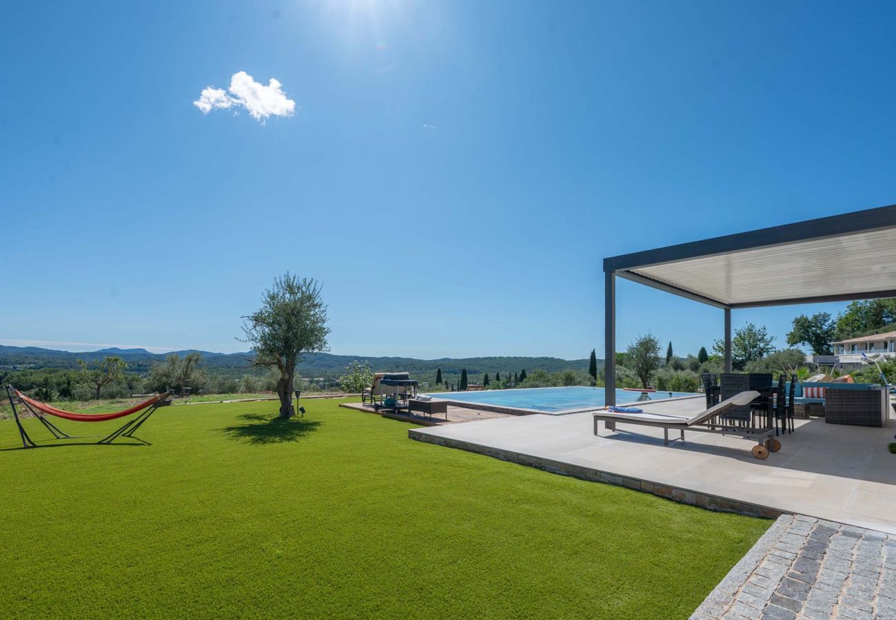 Rasen mit Hängematte, Infinity-Pool, überdachter Terrasse und Bergblick bei der Villa Belletoile in der Provence.