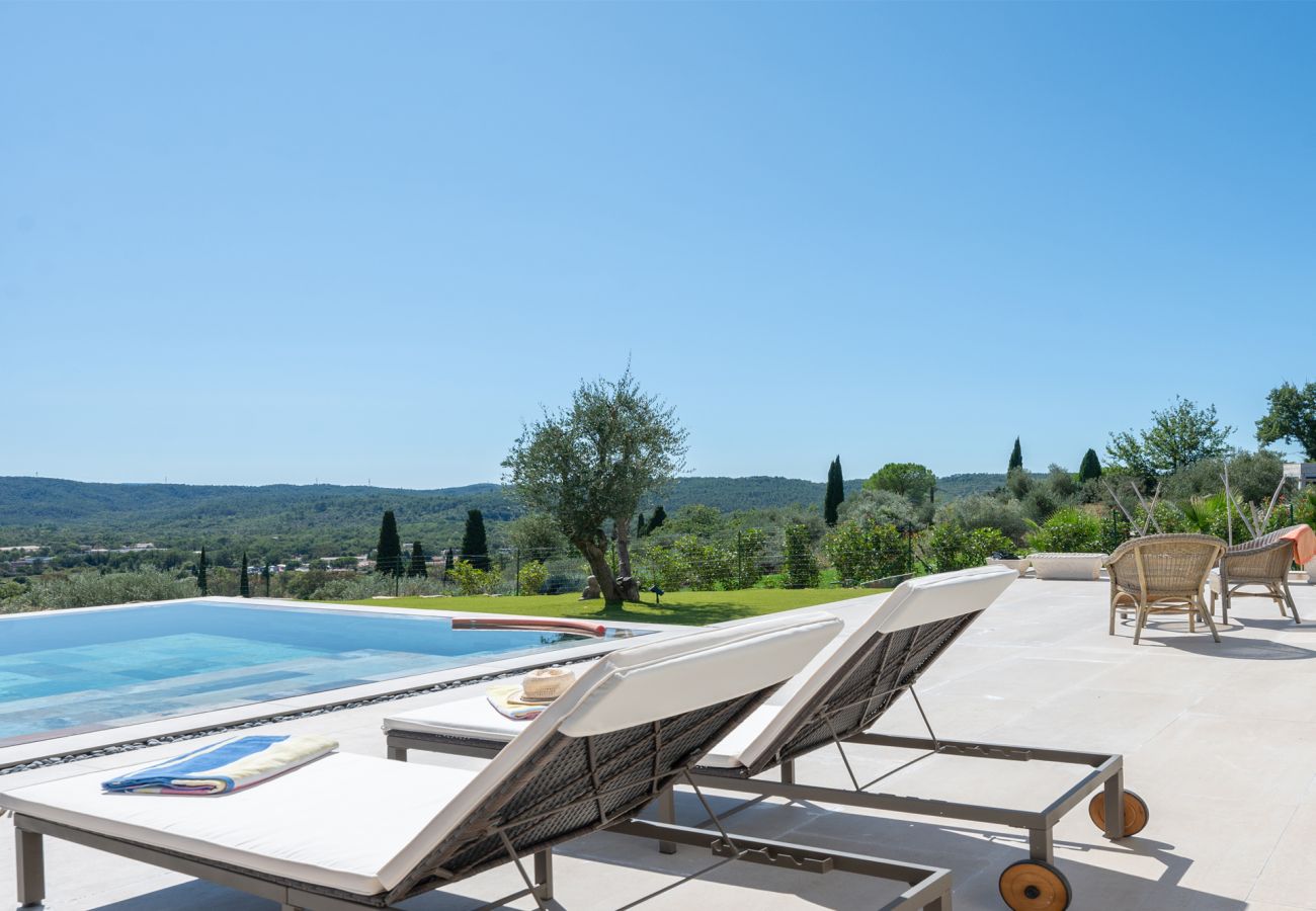 Stilvolle Terrasse mit zwei Liegen, Rattanstühlen und Infinity-Pool bei der Villa Belletoile in der Provence.